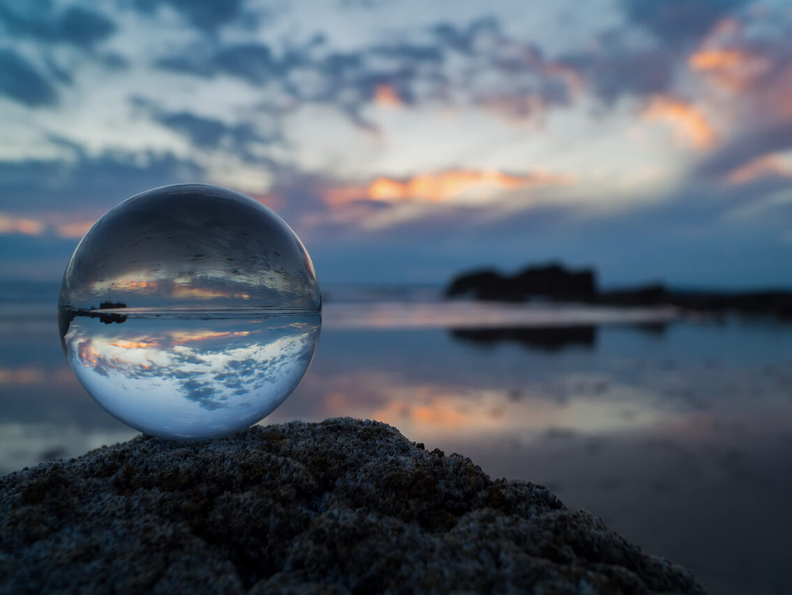 Clear glass globe by Phil Dolby capturing the ocean view, symbolizing the importance of reflection during an annual review.