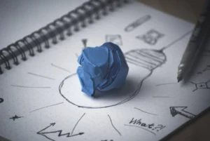 A lightbulb sketch and crumpled blue paper in a notebook, symbolizing the creative foundations of purpose-led strategic planning.